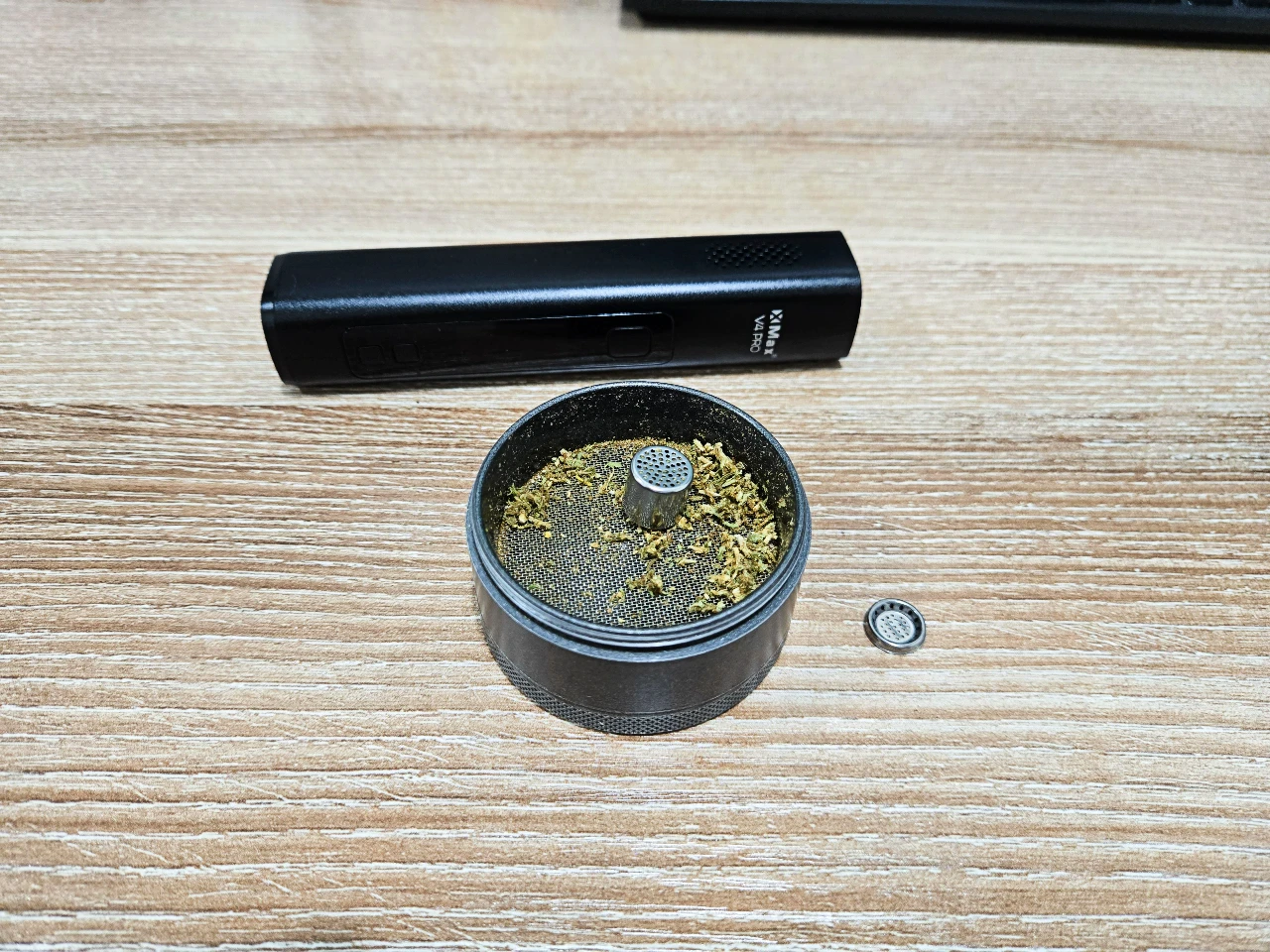 XMAX V4 Pro vaporizer with herb grinder, dosing capsule, and ground dry herbs